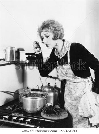 stock-photo-young-woman-in-an-apron-in-her-kitchen-tasting-her-food-from-a-pot-99451211